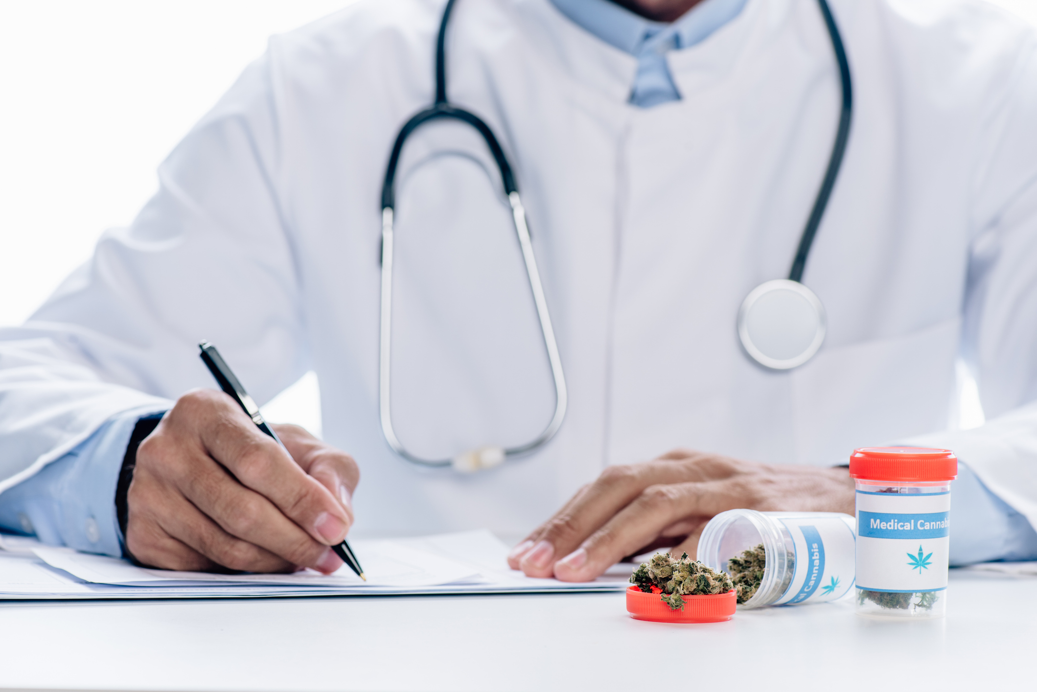 Doctor writing on checklist with medicinal cannabis container in foreground
