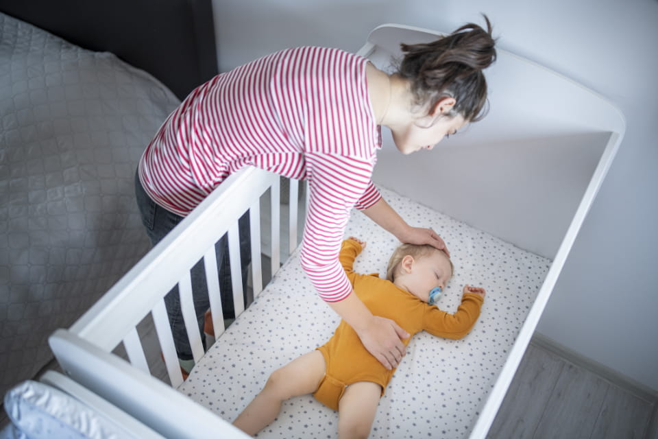 Woman putting baby to sleep in crib
