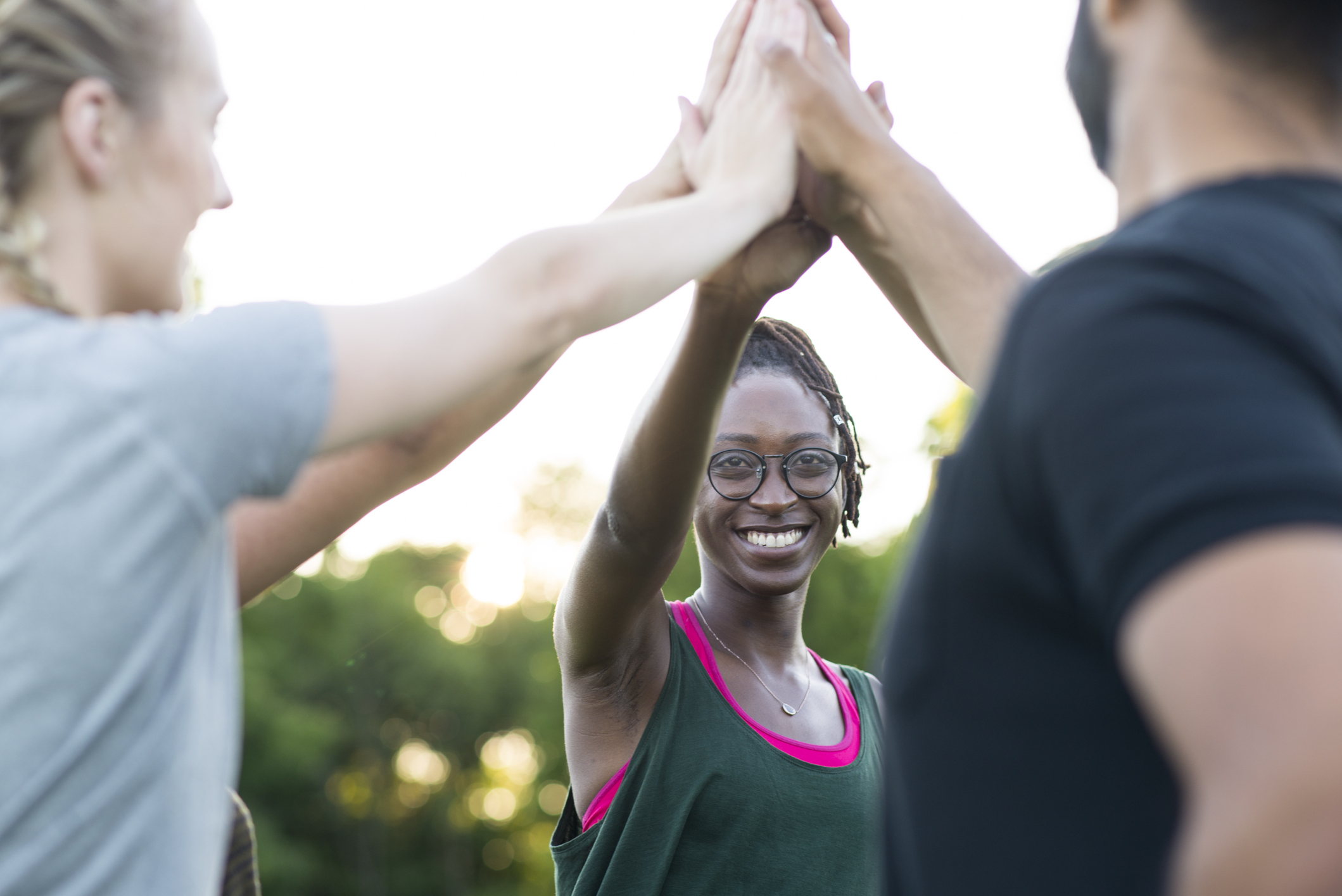 Group of people high-fiving with someone smiling in the middle