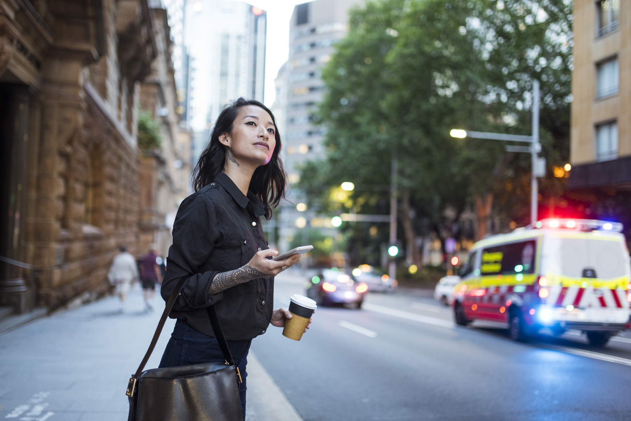 Woman in city with ambulance in background