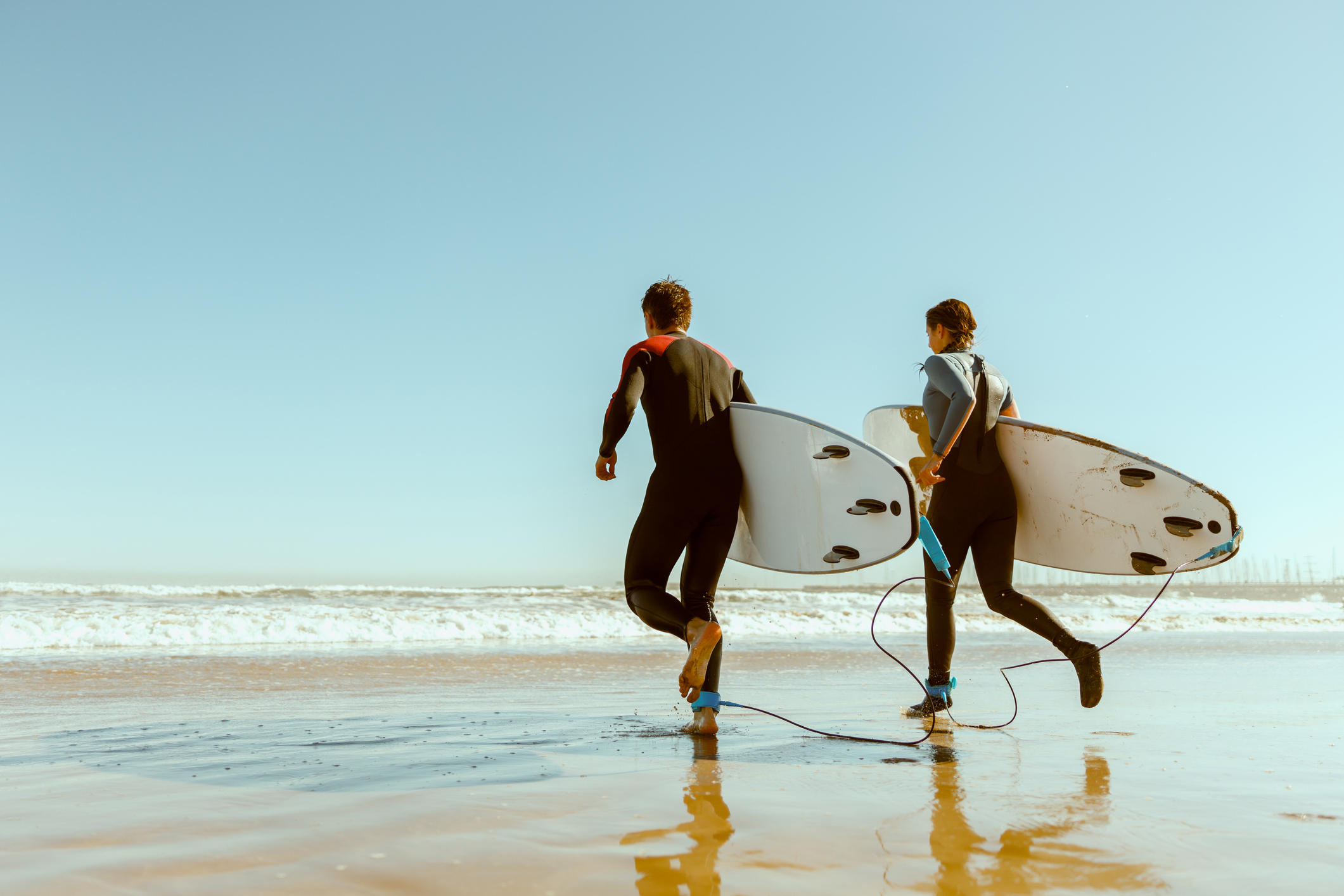 Two surfers running into the water